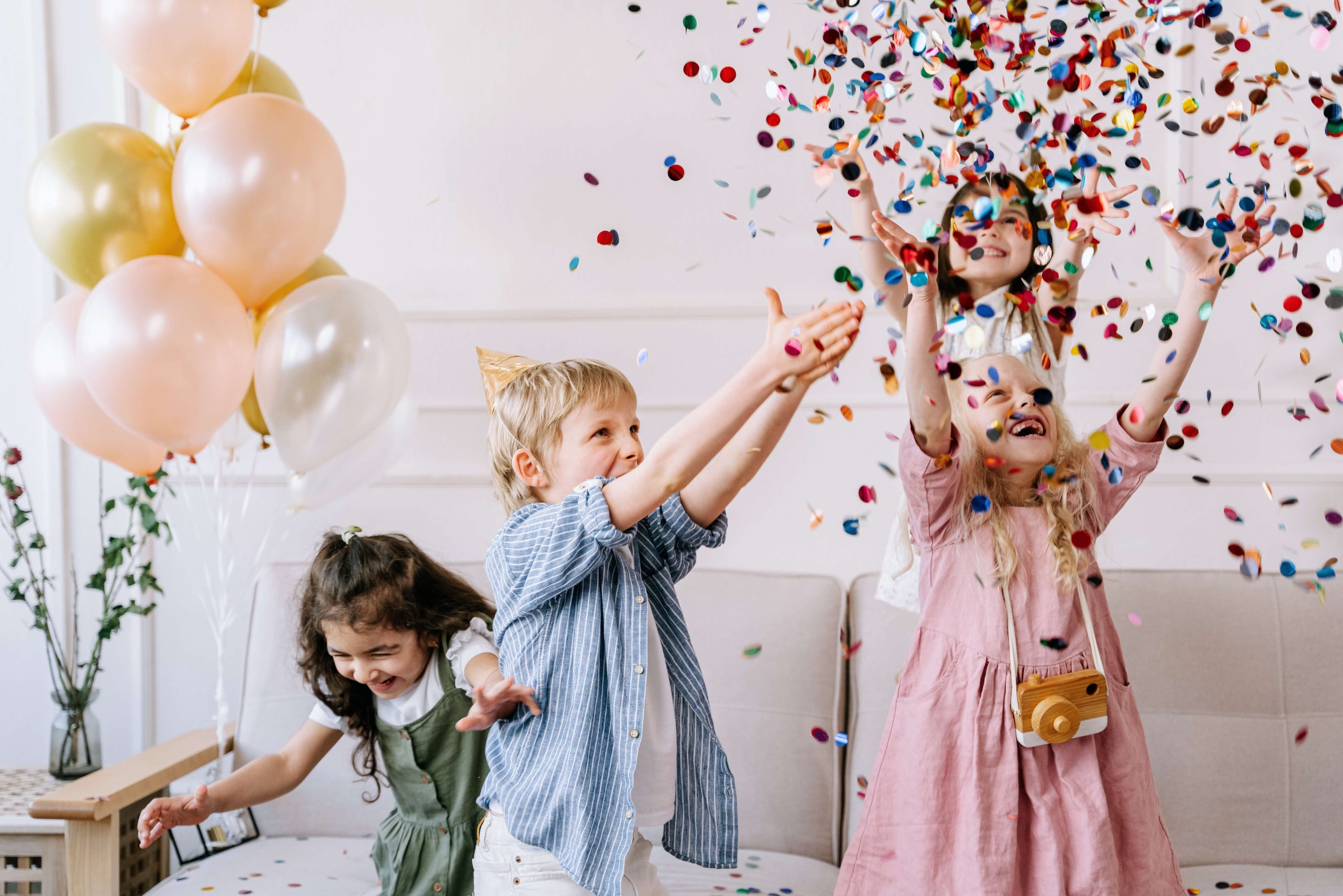 kids in lounge with ballloons in background and confetti in the air 